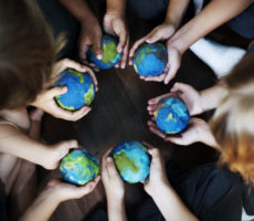 Group of diverse kids hands holding cupping globe balls together