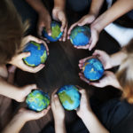 Group of diverse kids hands holding cupping globe balls together